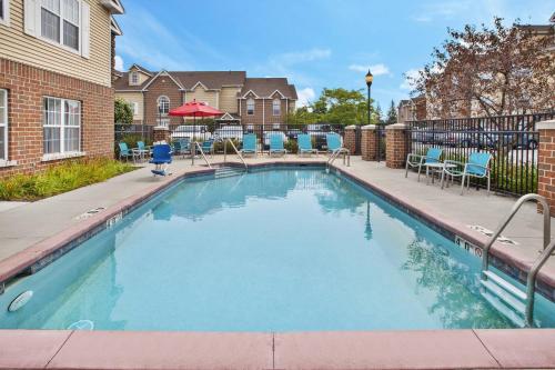 a swimming pool with blue chairs and a building at TownePlace Suites by Marriott Brookfield in Brookfield