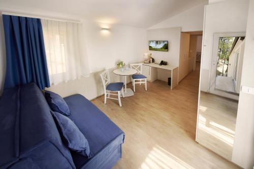 a living room with a blue couch and a table at Olive Family Suites - Hotel & Resort Adria Ankaran in Ankaran