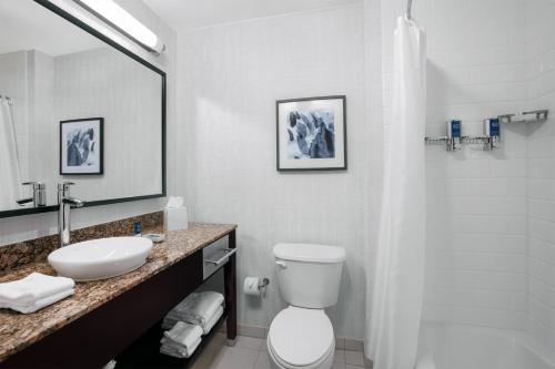 a bathroom with a sink and a toilet and a mirror at Four Points by Sheraton Fort Lauderdale Airport - Dania Beach in Dania Beach