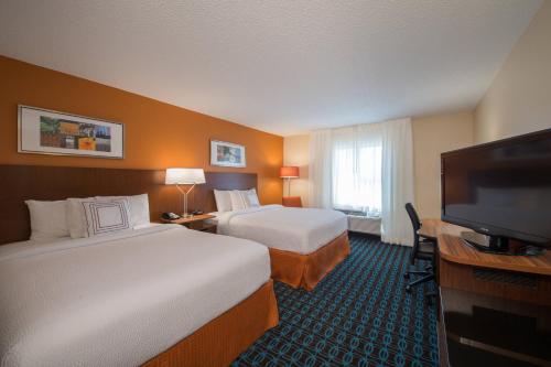 a hotel room with two beds and a flat screen tv at Fairfield Inn & Suites Dallas Lewisville in Lewisville