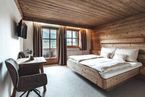 a bedroom with a bed and a desk in a room at Hotel Chalets Grosslehen in Fieberbrunn