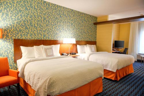 a hotel room with two beds and a chair at Fairfield Inn and Suites Canton South in Canton