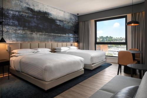 a bedroom with two beds and a large window at Johannesburg Marriott Hotel Melrose Arch in Johannesburg