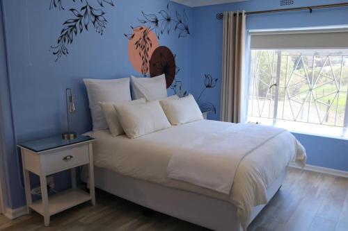 a bedroom with a large bed with a blue wall at Sunset Cottage - Cheerful 1 Bedroom Cottage in Barrydale