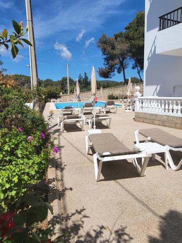 a row of lounge chairs and umbrellas on a patio at Apartamentos Mar Bella in Es Cana
