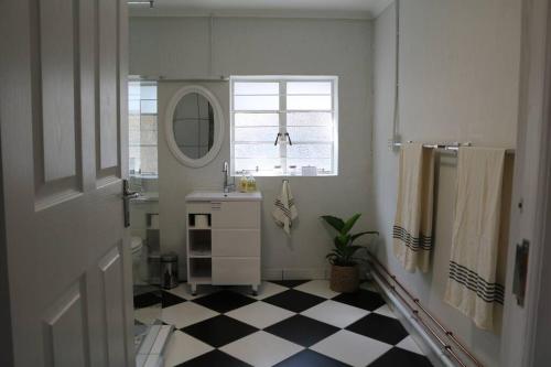 a bathroom with a black and white checkered floor at Sunset Cottage - Cheerful 1 Bedroom Cottage in Barrydale