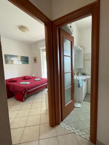 a bedroom with a red bed and a bathroom at Victoria's House in Rapallo