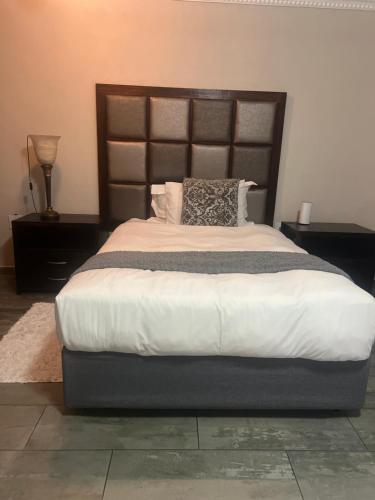 a bedroom with a large bed with a wooden headboard at VQS Guesthouse in Ermelo