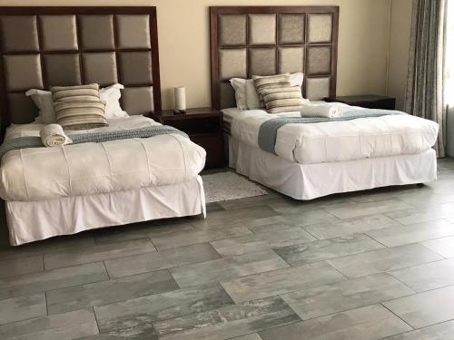 a bedroom with two beds and a tile floor at VQS Guesthouse in Ermelo