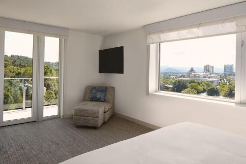 a bedroom with a bed and a chair and windows at Element Asheville Downtown in Asheville