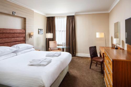 Habitación de hotel con cama grande y escritorio. en Delta Hotels by Marriott Cheltenham Chase en Cheltenham