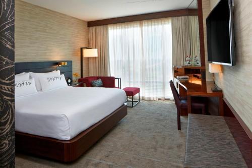 a hotel room with a bed and a desk and a television at Renaissance Dallas at Plano Legacy West Hotel in Plano