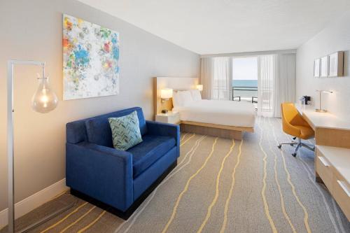 Habitación de hotel con cama y silla azul en Delta Hotels by Marriott Daytona Beach Oceanfront en Daytona Beach