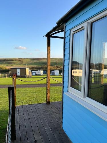 a blue house with a deck with a view of a field at Coral Shepherds Hut in Penally