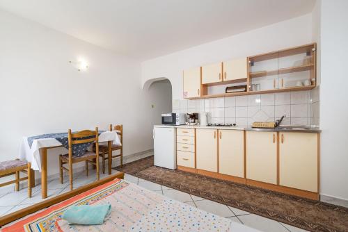 kuchnia z białymi szafkami i stołem w obiekcie Nice Apartment Silvia w Novalji