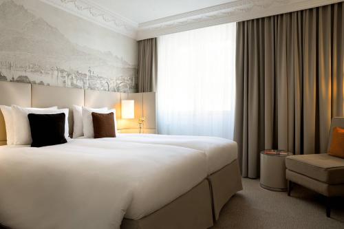 a hotel room with a large white bed and a chair at Renaissance Lucerne Hotel in Luzern