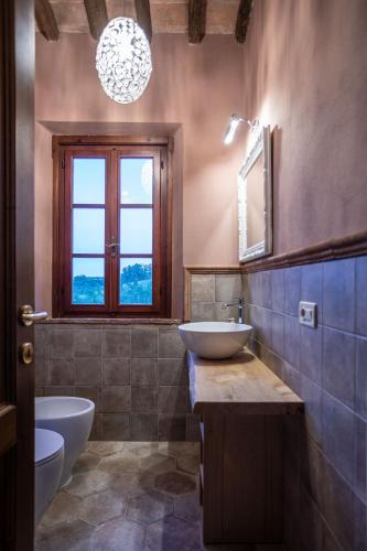 a bathroom with a sink and a toilet and a window at Fattoria Fibbiano in Terricciola