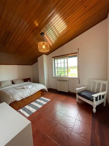 um quarto com uma cama e uma cadeira e um tecto de madeira em NO CEU - A fully private flat in the sky with Ocean view em Atouguia da Baleia