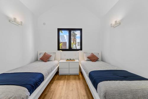 two beds in a room with white walls and wooden floors at Home2Book Design House Bastian Beach Costa Teguise in Costa Teguise