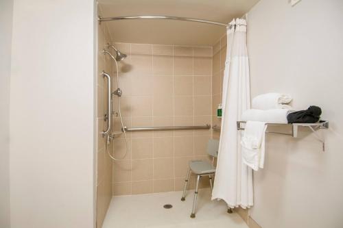 a bathroom with a shower with a chair and a shower curtain at Fairfield Inn & Suites by Marriott Dallas DFW Airport South/Irving in Irving