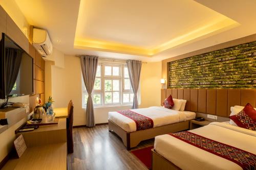 Cette chambre comprend deux lits et une télévision. dans l'établissement Avocado Orchid Resort, à Heṭauḍā