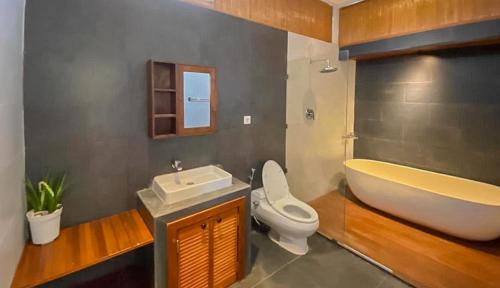 y baño con bañera, aseo y lavamanos. en The Lavana Villa Sutji Sanur, en Sanur