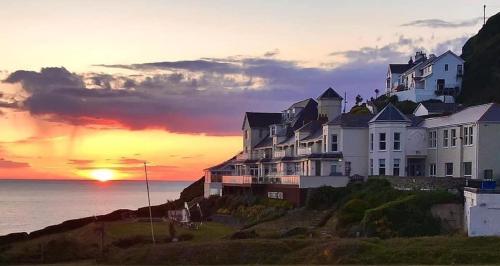 a building on a hill with the sunset in the background at Watersmeet Hotel in Woolacombe