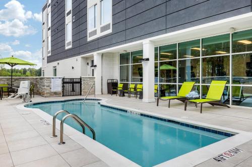 a swimming pool with yellow chairs next to a building at SpringHill Suites Charlotte Southwest in Charlotte