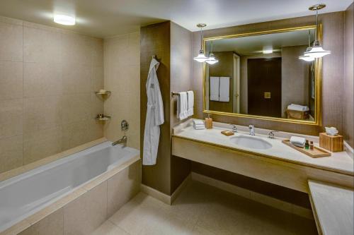 a bathroom with a tub and a sink and a mirror at The Plaza Hotel Columbus at Capital Square in Columbus