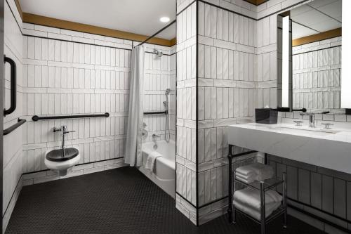 a bathroom with a toilet and a sink and a tub at The Union Club Hotel at Purdue University, Autograph Collection in West Lafayette