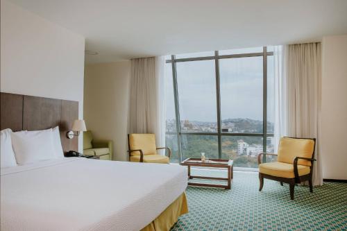 a hotel room with a bed and a large window at Courtyard by Marriott Guayaquil in Guayaquil