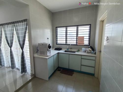 uma pequena cozinha com um lavatório e uma janela em Homestay Nilai D'Jati em Nilai