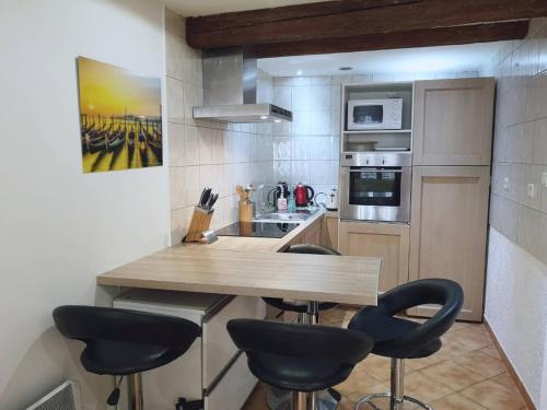 - une petite cuisine avec un comptoir en bois et des tabourets dans l'établissement Studio Centre Historique Aix-en-Provence, à Aix-en-Provence