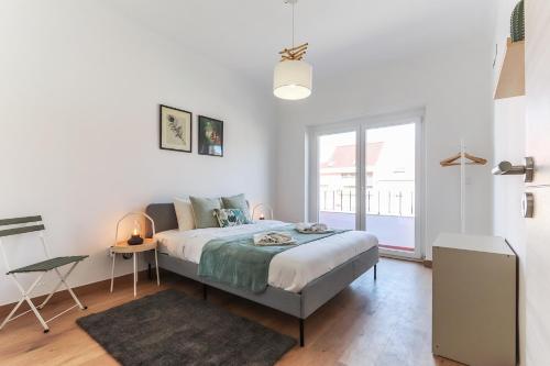 a white bedroom with a bed and a window at Vita Portucale ! Almada Balcony in Almada