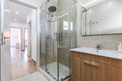 een badkamer met een glazen douche en een wastafel bij Vita Portucale ! Almada Balcony in Almada