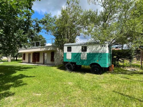 una roulotte verde e bianca parcheggiata di fronte a una casa di Residence Safari Resort - Magic Bus a Borovany