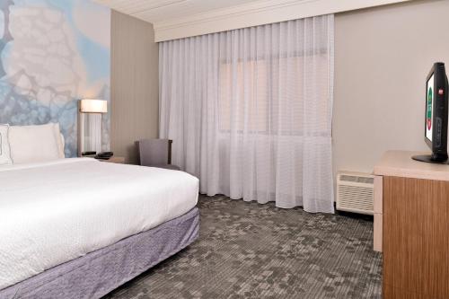 a hotel room with a bed and a flat screen tv at Courtyard by Marriott Dallas Northwest in Dallas