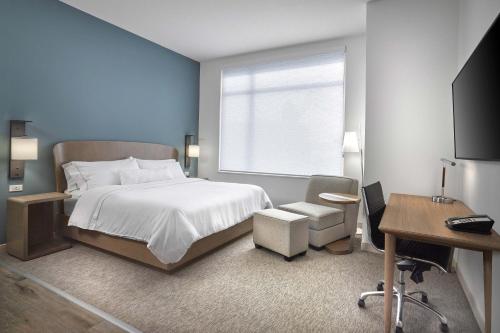 a bedroom with a bed and a desk and a window at Element Hampton Peninsula Town Center in Hampton
