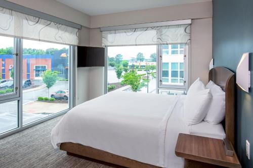a bedroom with a large bed and large windows at Element Hampton Peninsula Town Center in Hampton