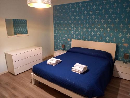 1 dormitorio con 1 cama azul y 2 toallas en CASA VACANZE FRANCIACORTA en Colombaro