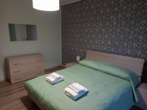 a bedroom with a green bed with two towels on it at CASA VACANZE FRANCIACORTA in Colombaro