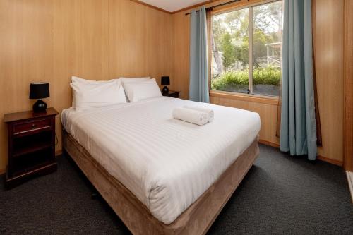 a bedroom with a large white bed with a window at BIG4 Iluka on Freycinet in Coles Bay