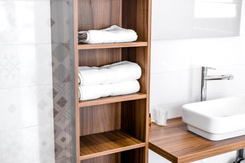 baño con estante de madera con toallas y lavamanos en Hôtel Beau Site en Le Lavandou