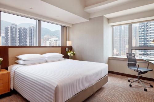 Habitación de hotel con cama, silla y ventanas en Courtyard by Marriott Hong Kong, en Hong Kong