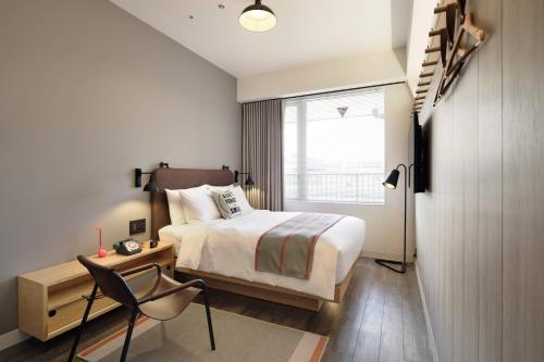 1 dormitorio con cama, escritorio y ventana en MOXY Tokyo Kinshicho en Tokio