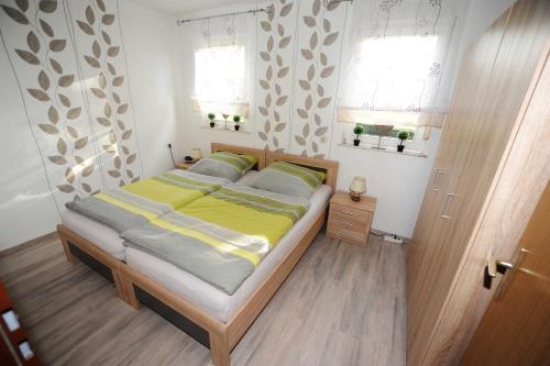 een slaapkamer met een bed met gele en grijze lakens bij Ferienwohnung Wiesenblick, 65322 in Moormerland