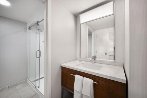 Baño blanco con lavabo y espejo en Courtyard Mobile, en Mobile