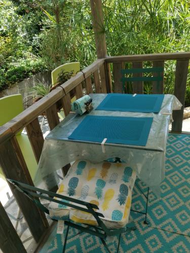 a table and chairs on a deck with a pillow at Le P'tit gîte in Saint-Privat
