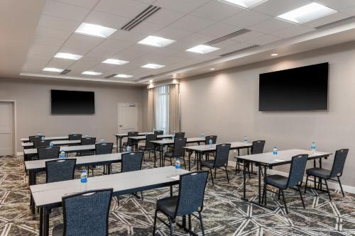 a conference room with tables and chairs and a screen at Residence Inn by Marriott Lancaster Palmdale in Lancaster