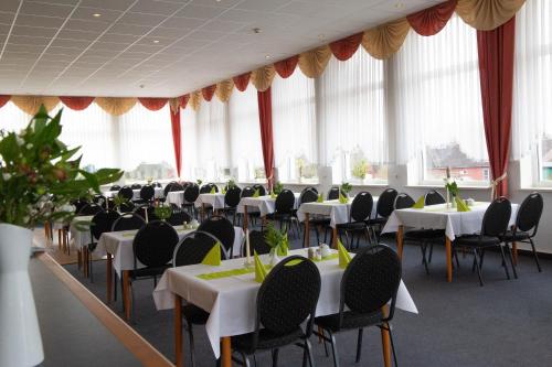 a banquet hall with tables and chairs and windows at Apartmenthotel-Harz in Friedrichsbrunn